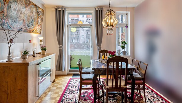 Un coin repas avec une table dressée pour quatre personnes, un lustre et une vue par la fenêtre.