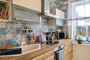 A kitchen with patterned tiles, a microwave, a stove, and a window with a plant.
