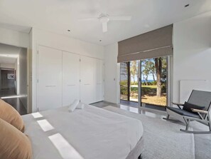 A bedroom with a bed, a chair, a wardrobe, and a view of the outdoors.