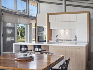 A modern kitchen with a central island, built-in ovens, and a large window.
