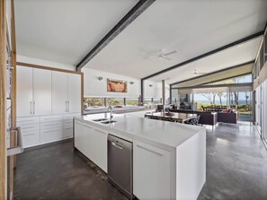 A modern kitchen with a large island, white cabinetry, and a view to the outdoors.
