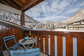 Un balcon avec une table et des chaises, donnant sur un paysage montagneux enneigé.