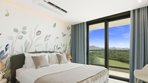 A bedroom with a large bed, a view of the outdoors, and a modern air conditioning unit.