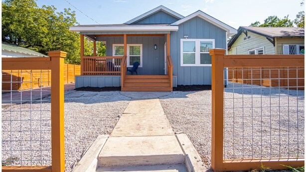 A single-story house with a porch, a covered entryway, and a fenced yard.