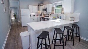A modern kitchen with a large island, bar stools, and a welcome sign.