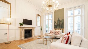 Un salon spacieux avec une cheminée, un canapé, une table basse et un lustre.