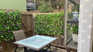 A patio with a table and chairs, surrounded by a wooden fence and lush greenery. - TXST Cozy and centrally located (San Marcos)