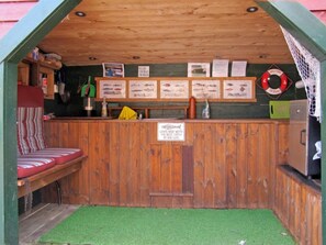 A small, wooden fishing hut with a green roof, a bench, and a sign that reads "Fisherman lives here with the best catch of his life." - Kalavåg by Interhome (Langevåg)