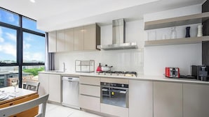 A modern kitchen with a large window, stainless steel appliances, and a dining area with a view. - MetaWiseBnB|Sydney CBD|Chinatown|Luxe 2Bed Penthouse Bella (Haymarket)