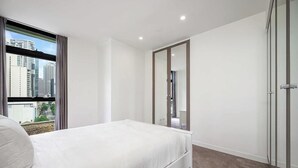 A modern bedroom with a large window, a bed, a wardrobe, and a mirror. - MetaWiseBnB|Sydney CBD|Chinatown|Luxe 2Bed Penthouse Bella (Haymarket)