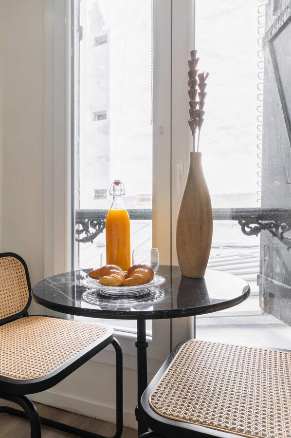 A table with croissants, a glass of orange juice, and a vase.