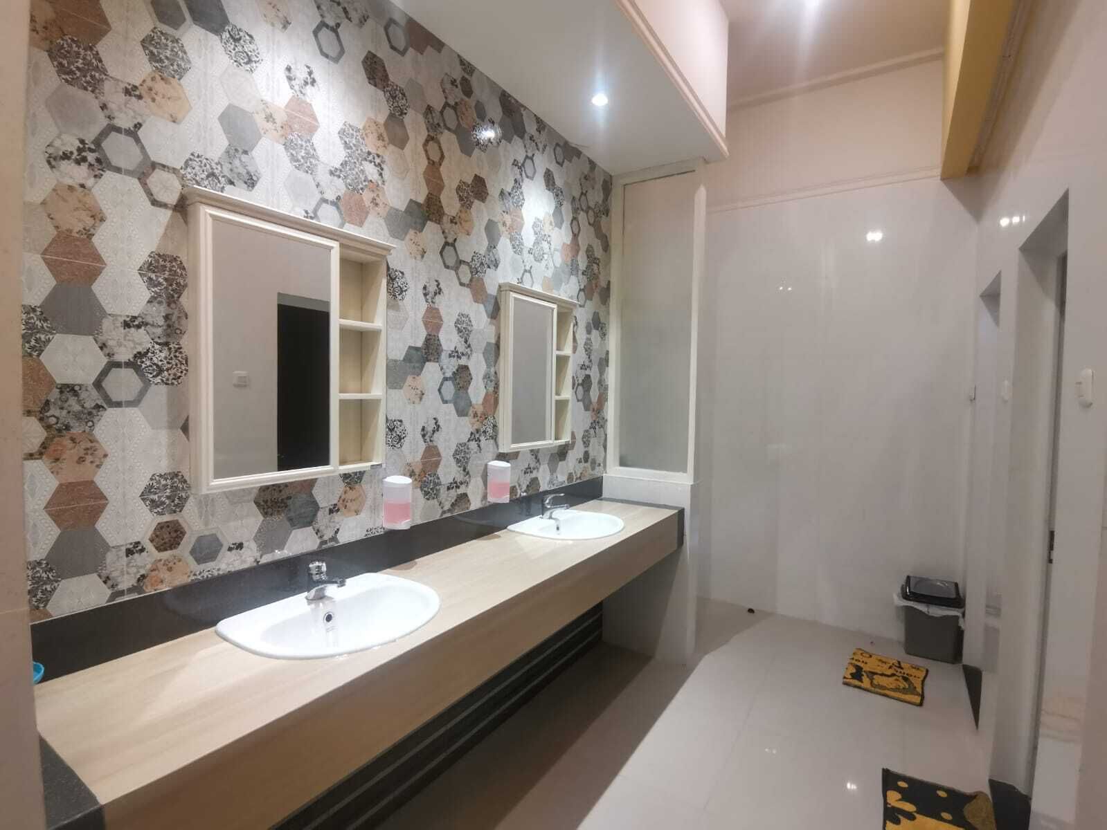 A modern bathroom with two sinks, a large mirror, and a hexagonal patterned wall.