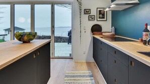 A modern kitchen with a large window, a bowl on the counter, and a bottle of wine. - "Lika" - 25m to the fjord by Interhome (Nordborg)