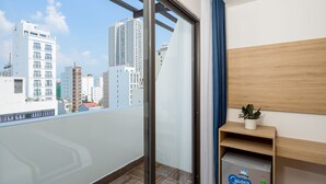 A balcony with a city view, a wooden shelf with a plant, and a refrigerator. - Doji Stars (Da Nang)