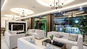 A modern living room with a marble fireplace, comfortable sofas, a flat-screen TV, and a large window offering a city view. - Doji Stars (Da Nang)