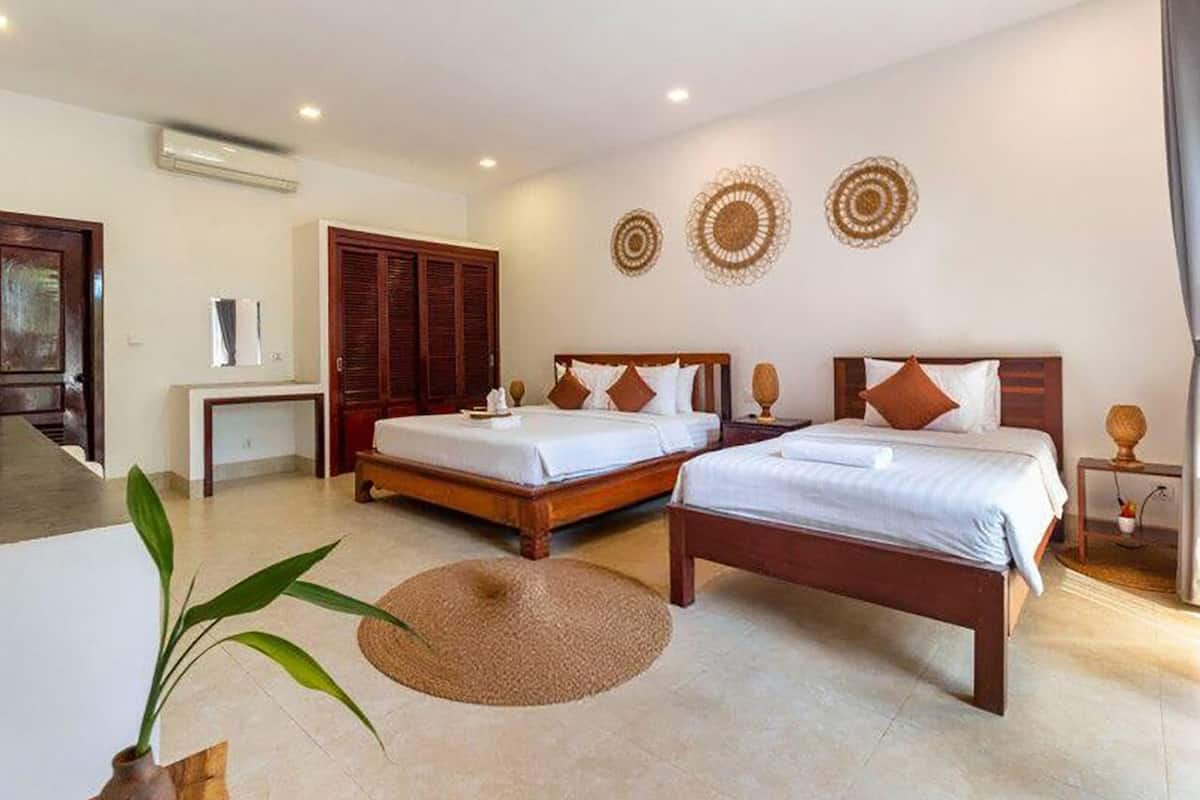 Une chambre d’hôtel avec deux lits, un coin salon et une petite table.