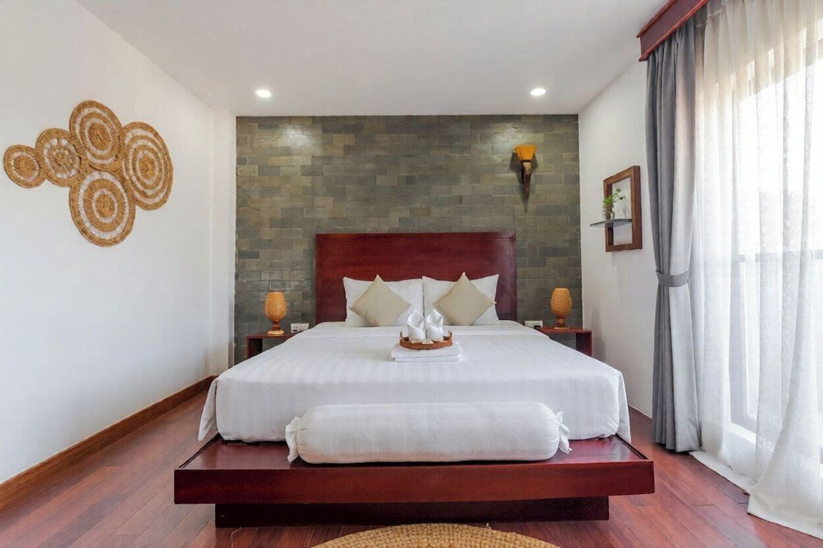 Une chambre spacieuse avec un grand lit, un mur en pierre et une vue sur l’extérieur.