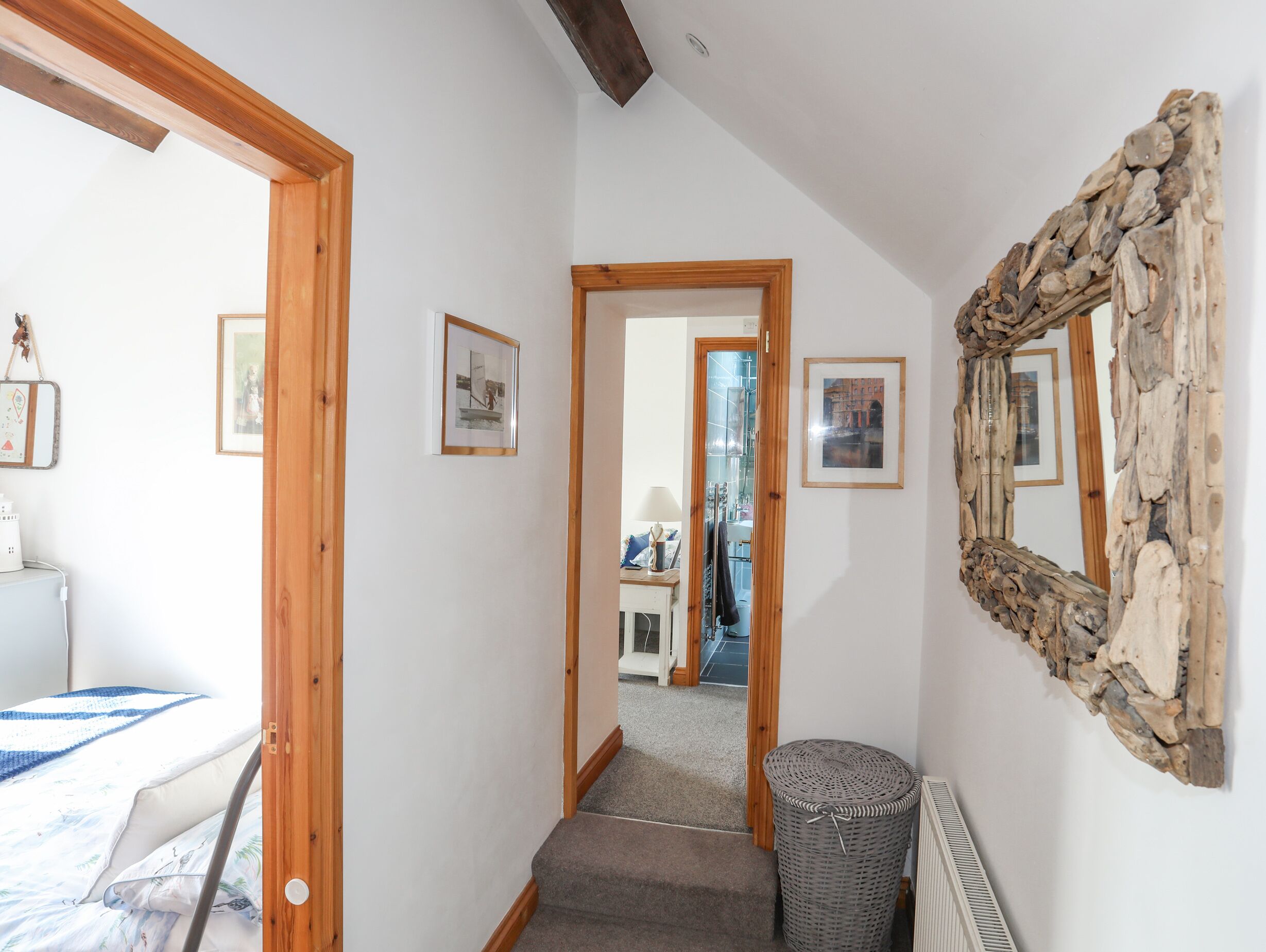 A hallway with a wooden door, a stone-framed mirror, and a bed with a blue and white bedspread.
