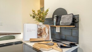 A kitchen counter with a cookbook, a rolling pin, a pair of scissors, and a cutting board. - Starry Night Cabin at Sky Ranch (Oakhurst)