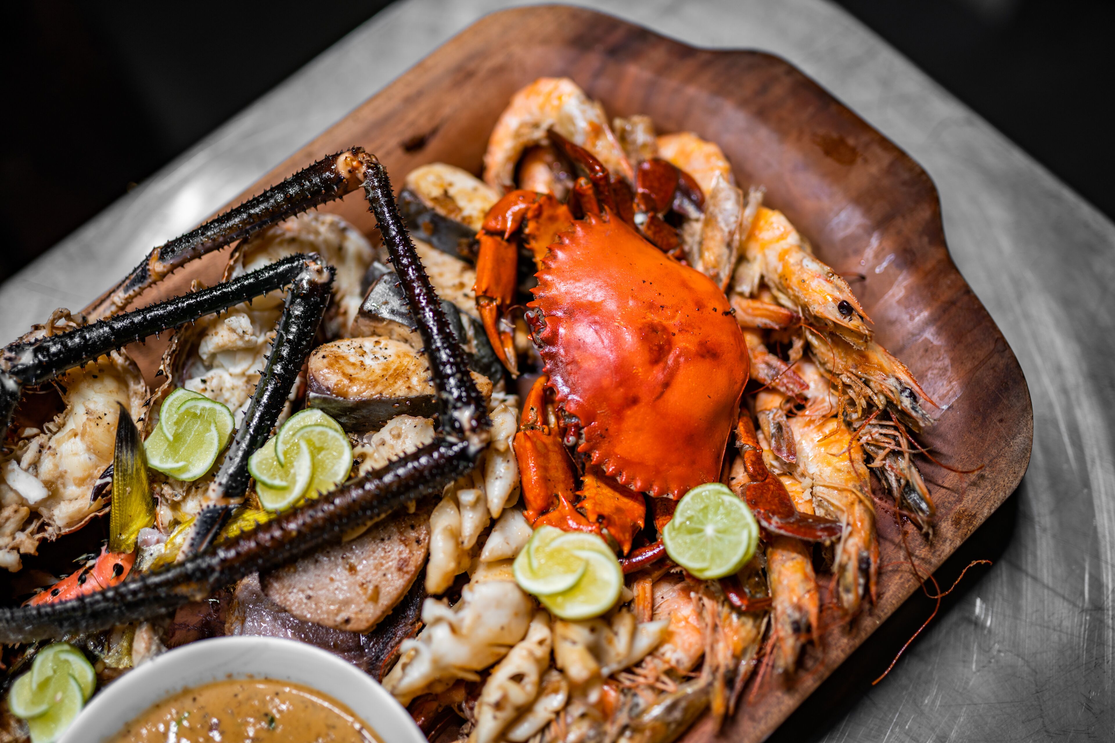 Un plateau de fruits de mer comprenant du crabe, des crevettes et du calmar, agrémenté de rondelles de citron vert.