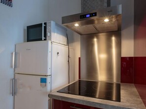 Een koelkast, een microgolfoven, een oven, kookgerei, borden en bestek