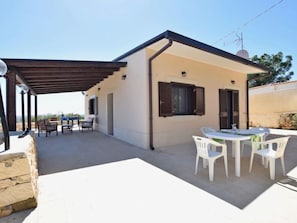 Une petite maison avec un patio, une table et des chaises, et un mur en pierre.