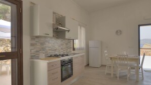 Eine moderne Küche mit Gasherd, Backofen und weißen Schränken. Ein Essbereich mit Tisch und Stühlen ist ebenfalls vorhanden.