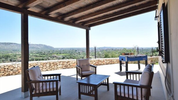 Eine Terrasse im Freien mit Holzmöbeln und einem Tisch, mit Blick auf eine malerische Landschaft.