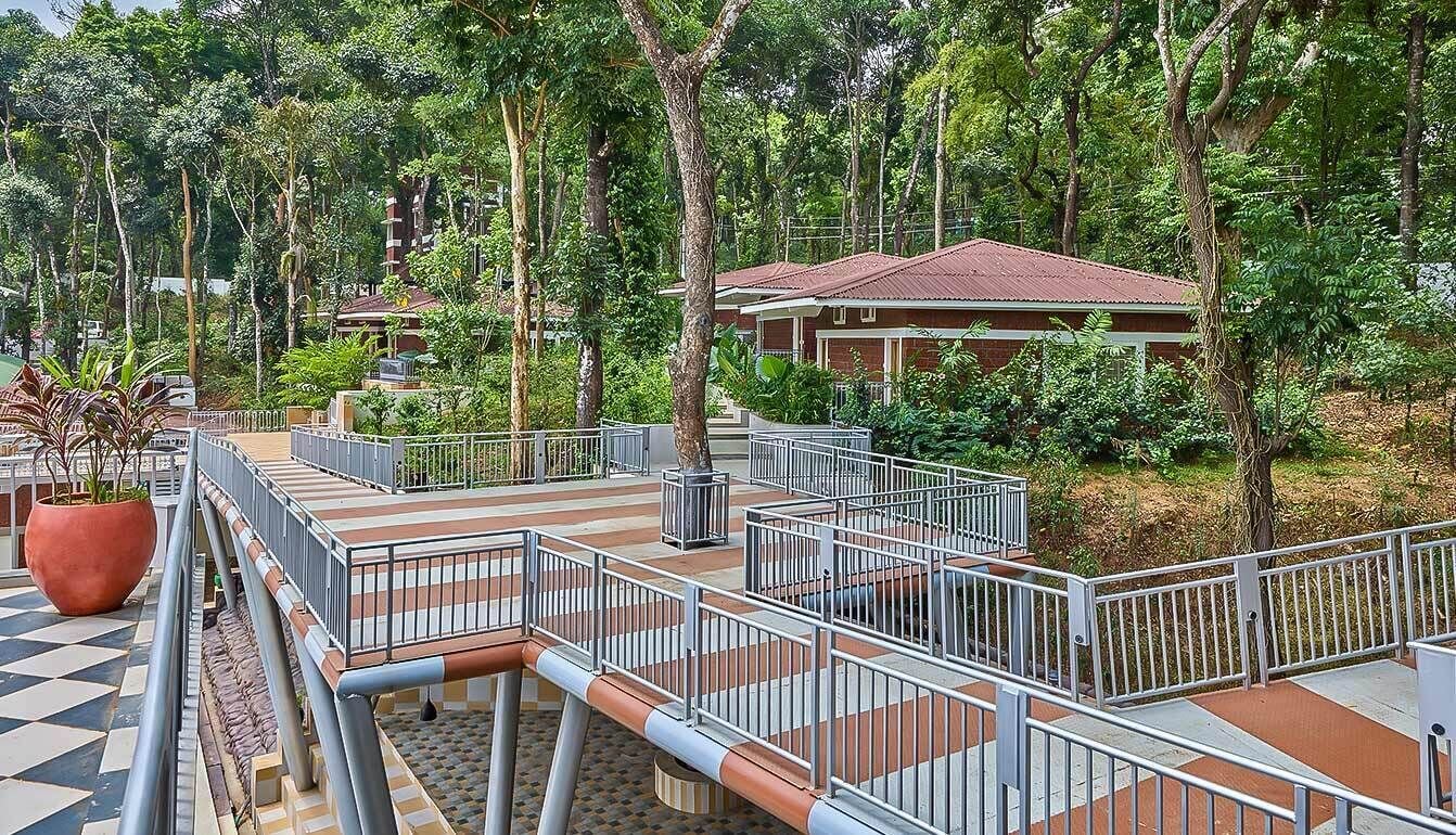 A multi-level outdoor area with a checkered floor pattern, metal railings, and a large potted plant.
