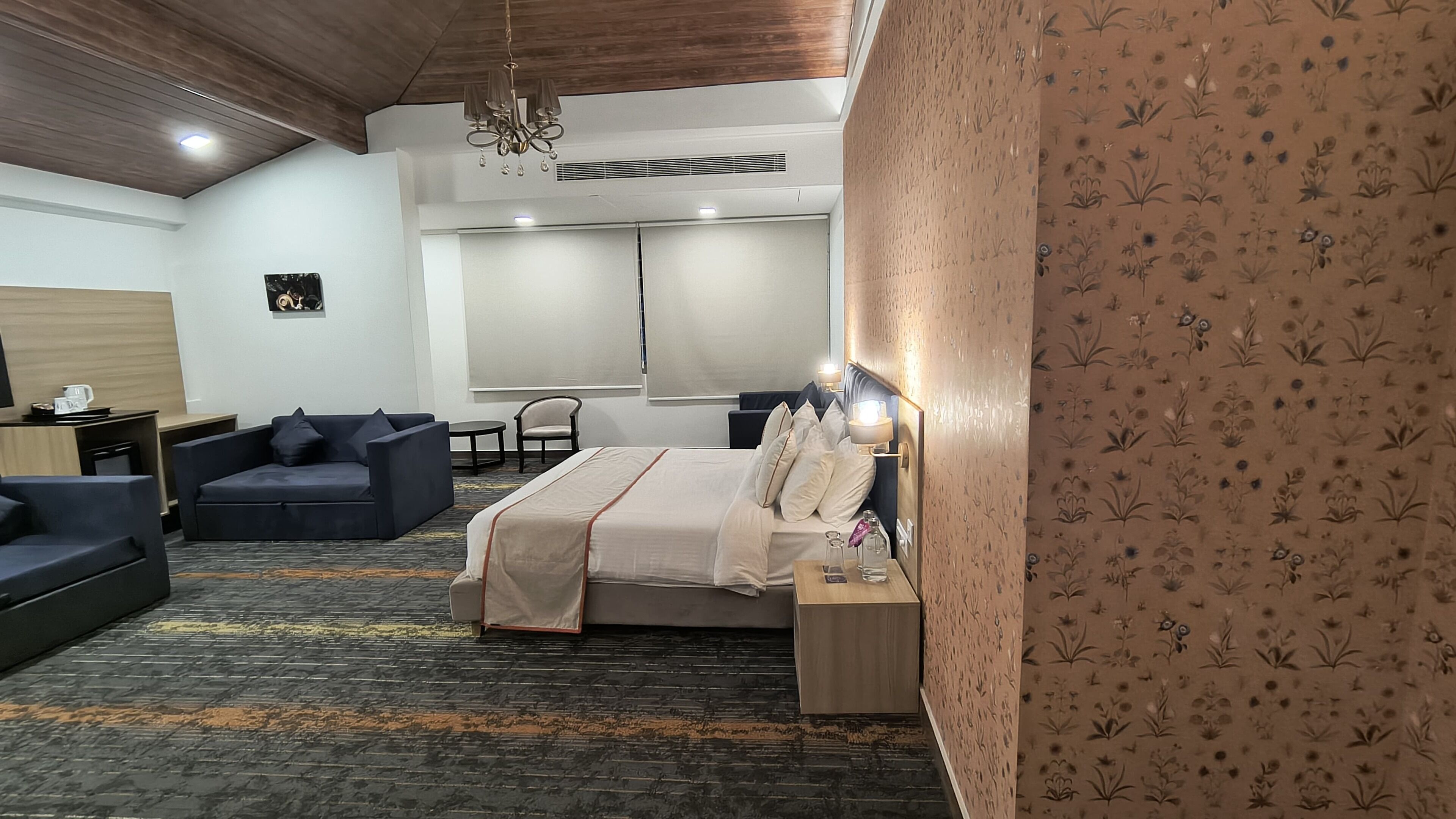 A hotel room with a bed, a sofa, a small table, and a chair.