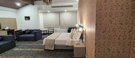 A hotel room with a bed, a sofa, a small table, and a chair.