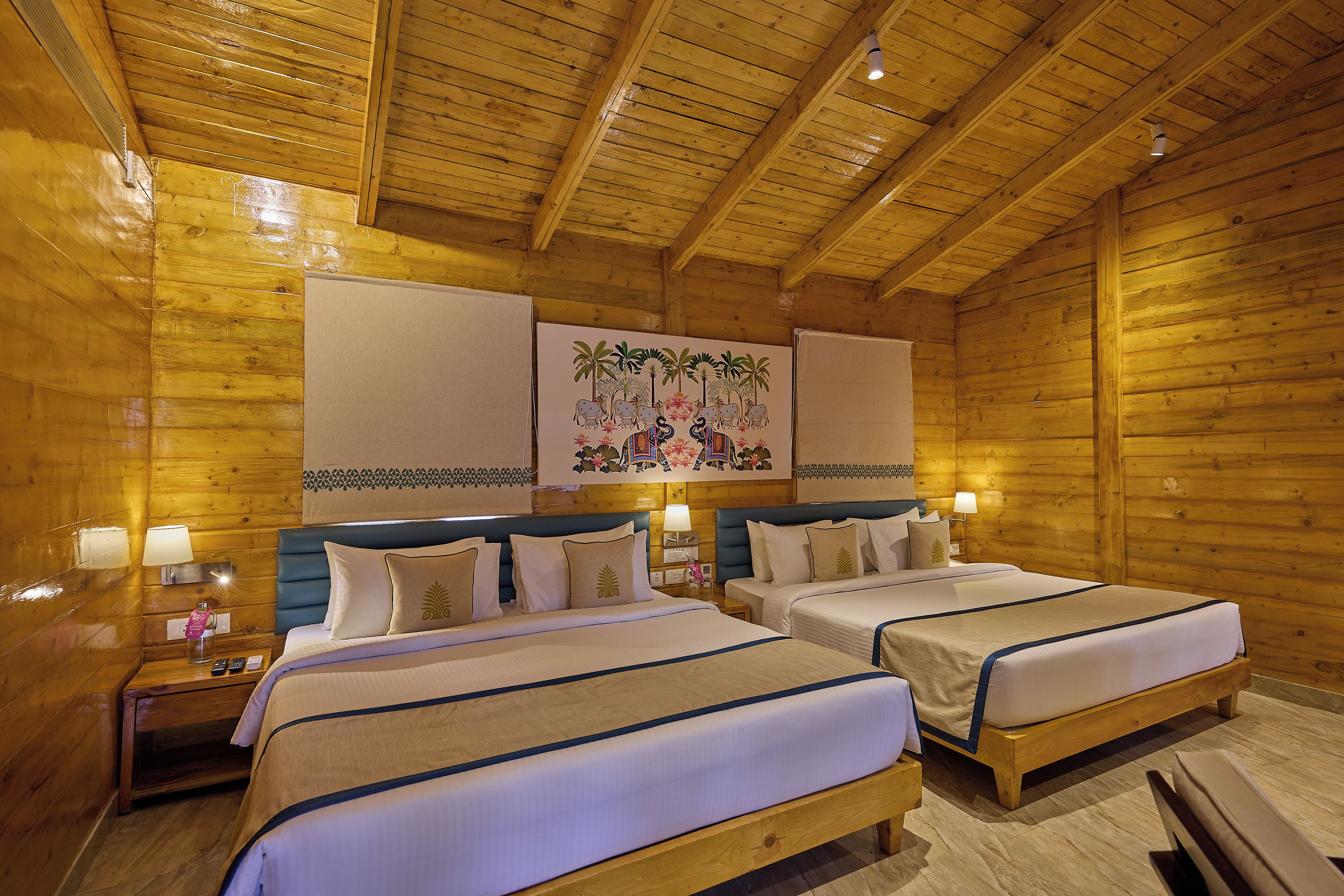 Quarto tipo cabana de madeira com duas camas, paredes de madeira e teto com vigas aparentes.