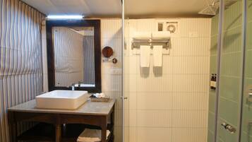 Un baño con un espejo grande, un lavabo y una zona de ducha.