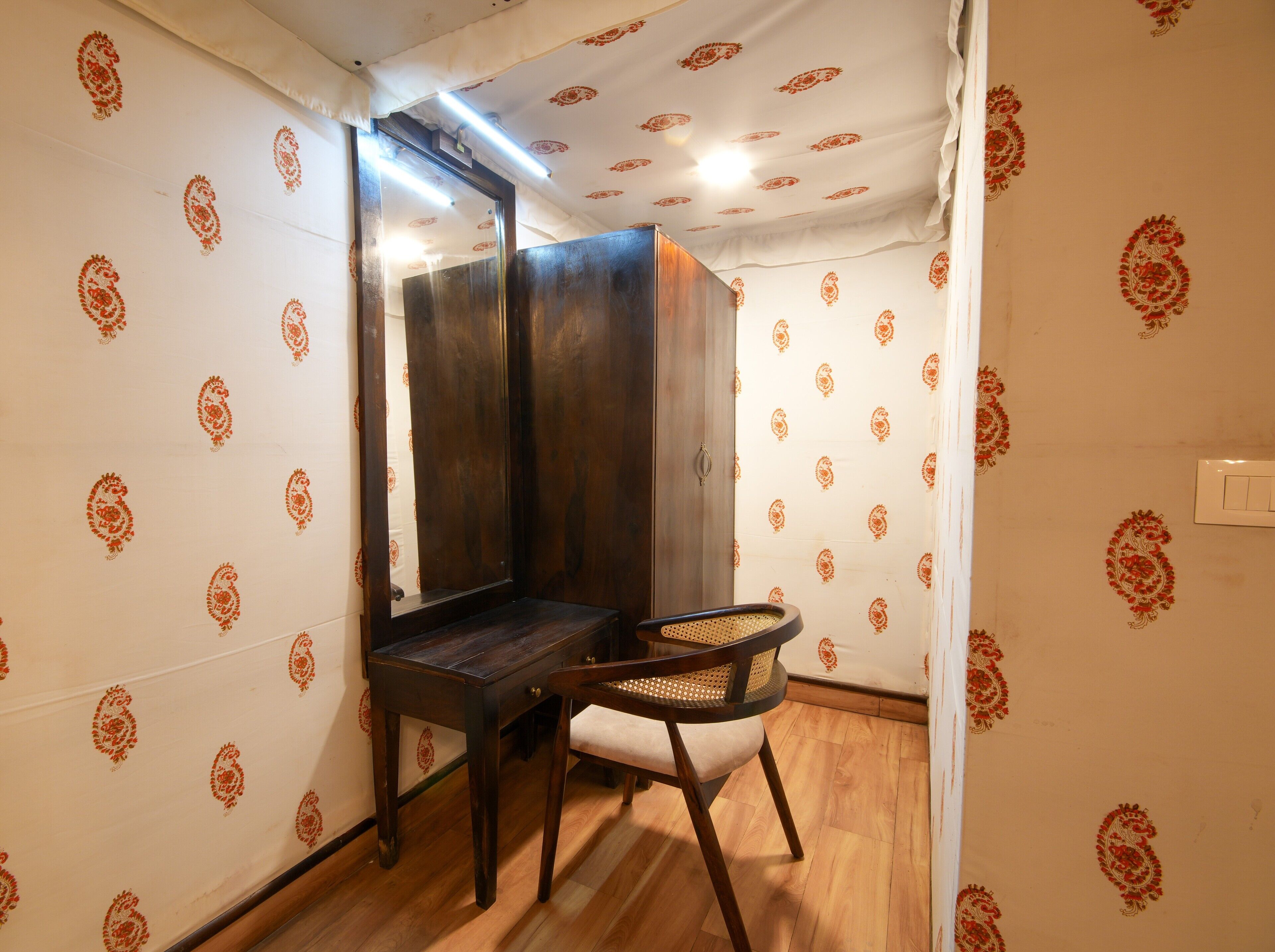A small, private bathroom with a wooden vanity, a mirror, and a chair.