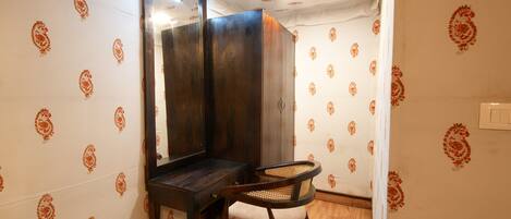 A small, private bathroom with a wooden vanity, a mirror, and a chair.