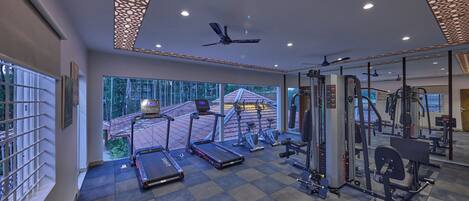 Une salle de sport moderne équipée de tapis de course, de vélos d’exercice et d’appareils de musculation.