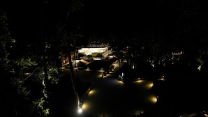 A nighttime view of a hotel with a well-lit entrance and a pool area. - Regenta Resort Sakleshpur (Sakleshpur)