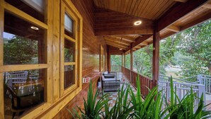 A wooden cabin with a covered porch, large windows, and a view of the surrounding forest. - Regenta Resort Sakleshpur (Sakleshpur)