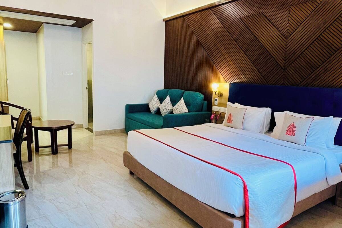 A bedroom with a bed, a sofa, a dining table, and a ceiling fan.