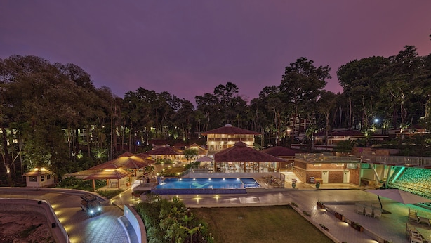 A resort with a swimming pool, outdoor seating, and a well-lit building. - Regenta Resort Sakleshpur (Sakleshpur)
