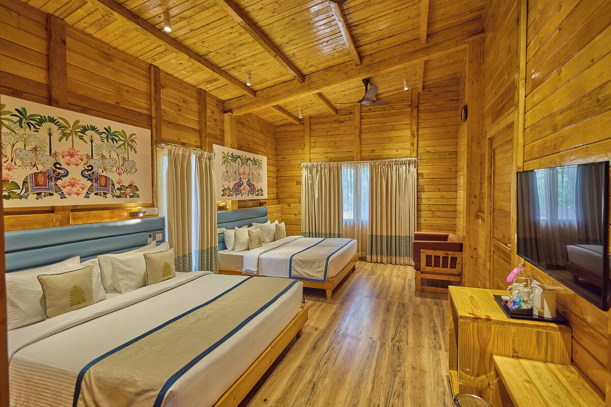 A wooden cabin-style room with three beds, a TV, and a small table with toiletries.