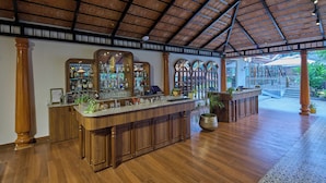 A spacious bar area with wooden cabinets, a long counter, and a patterned ceiling. - Regenta Resort Sakleshpur (Sakleshpur)