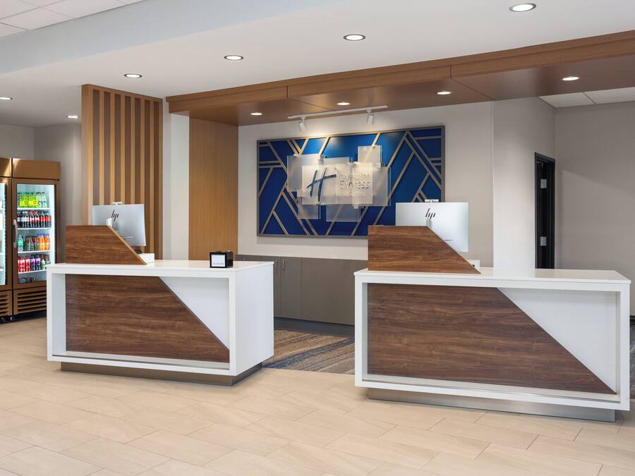 Un área de recepción con dos mostradores blancos, una pared azul con diseños geométricos y un panel de madera.