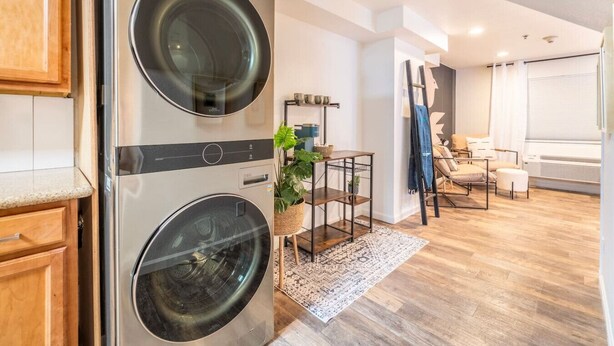 Eine moderne Küche mit integrierten Geräten, ein Essbereich mit Tisch und Stühlen sowie ein Wohnzimmer mit Sofa und Fenster.
