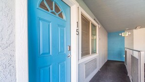 A hallway with a blue door, a window, and an exit sign. - Modern Haven: Chic Studio Getaway (Reno)
