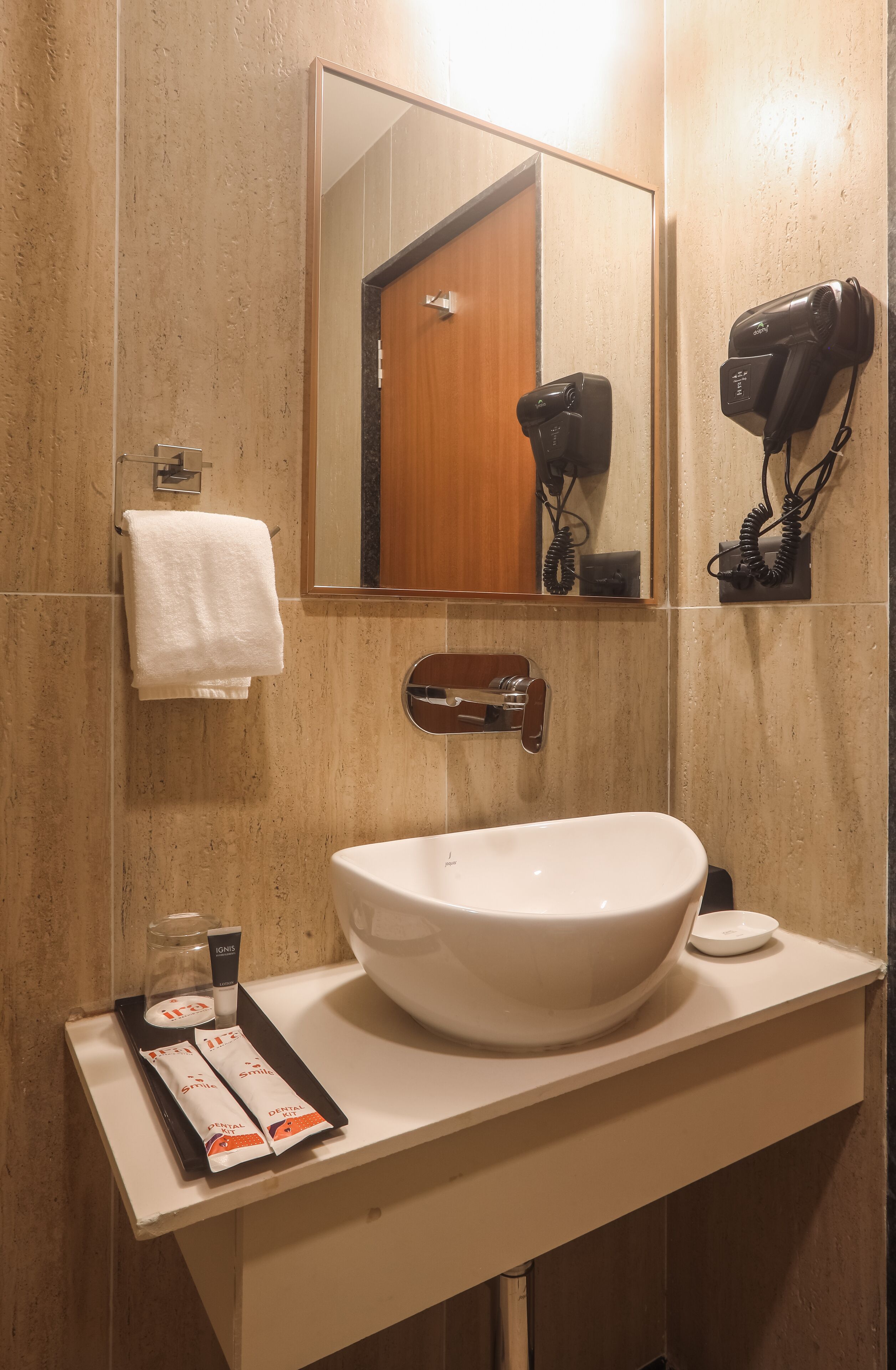 A bathroom with a large sink, a mirror, a towel rack, and a hairdryer mounted on the wall.