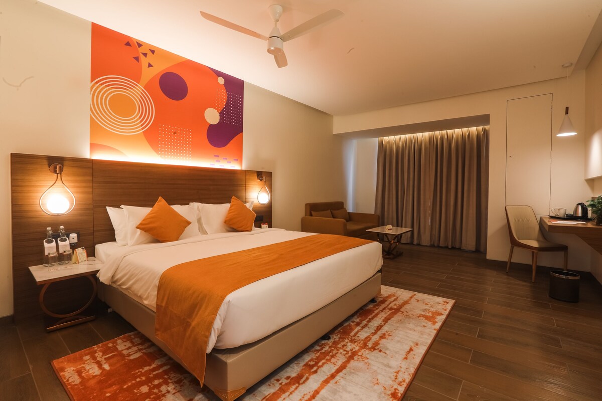 A modern hotel room with a large bed, a desk, and a chair.