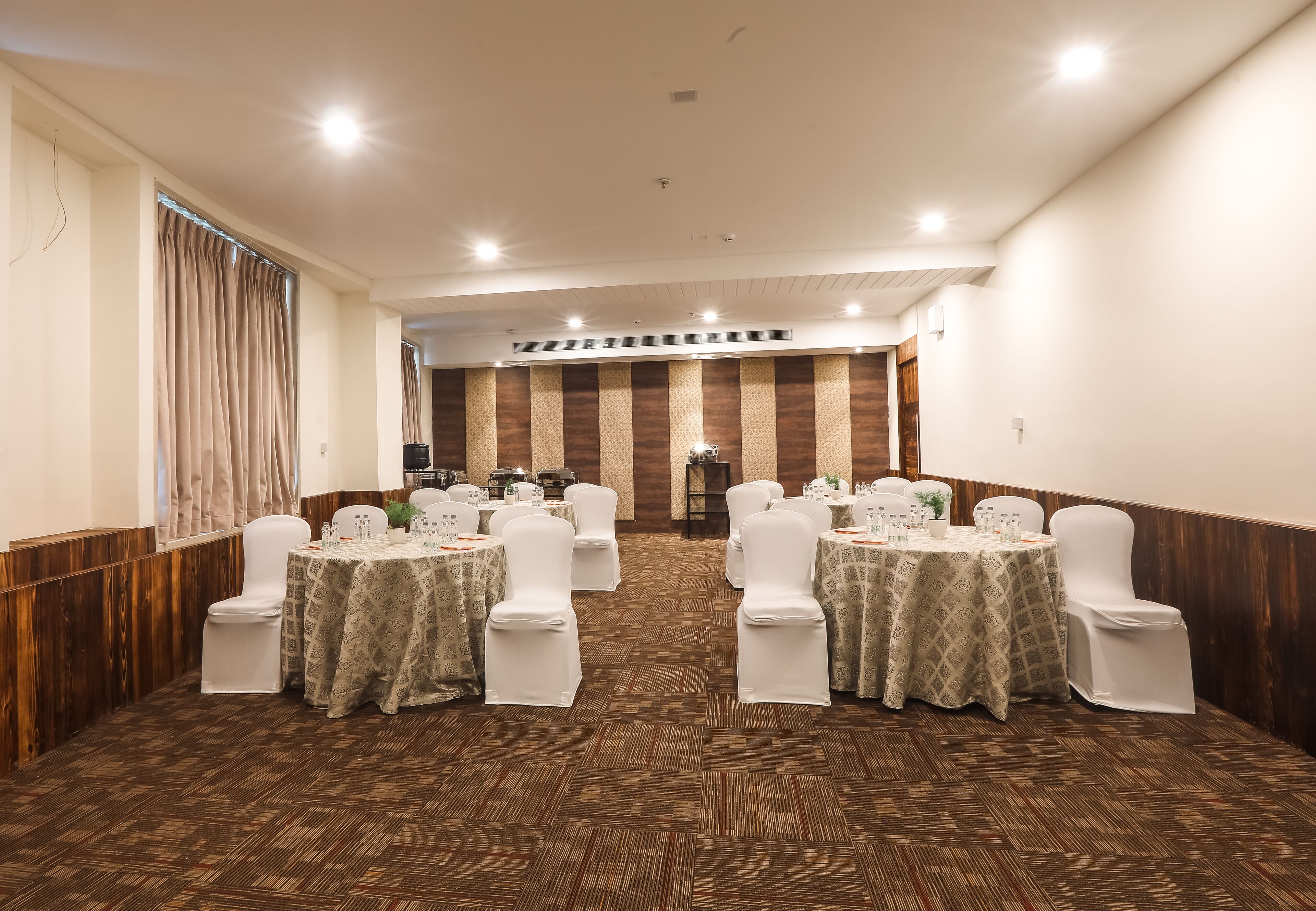 A conference room with multiple tables and chairs, arranged in rows.