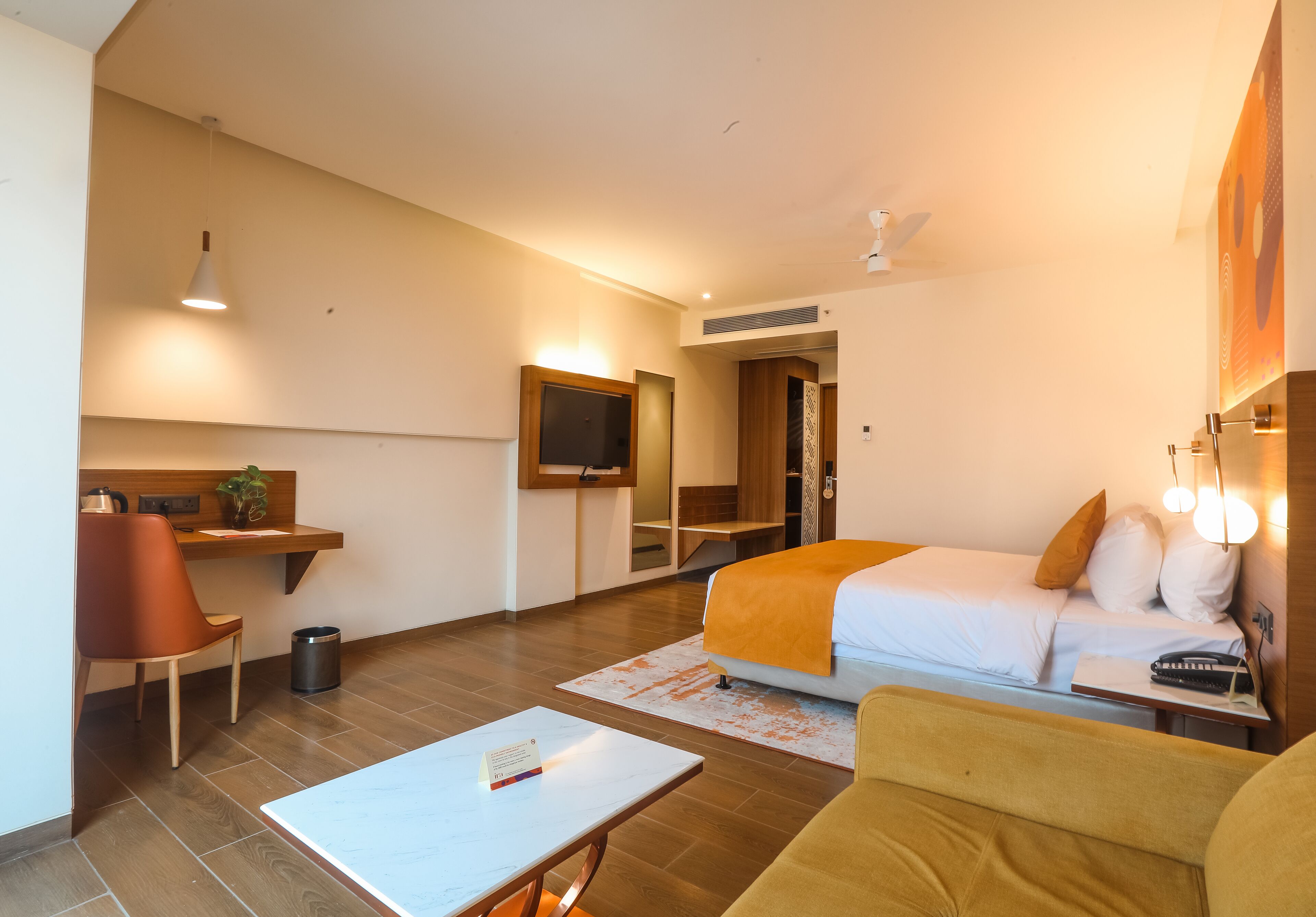 Habitación de hotel con una cama, un escritorio con una silla, una mesita y un televisor.
