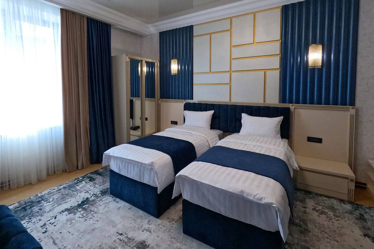 A hotel room with two beds, a large mirror, and a chandelier.